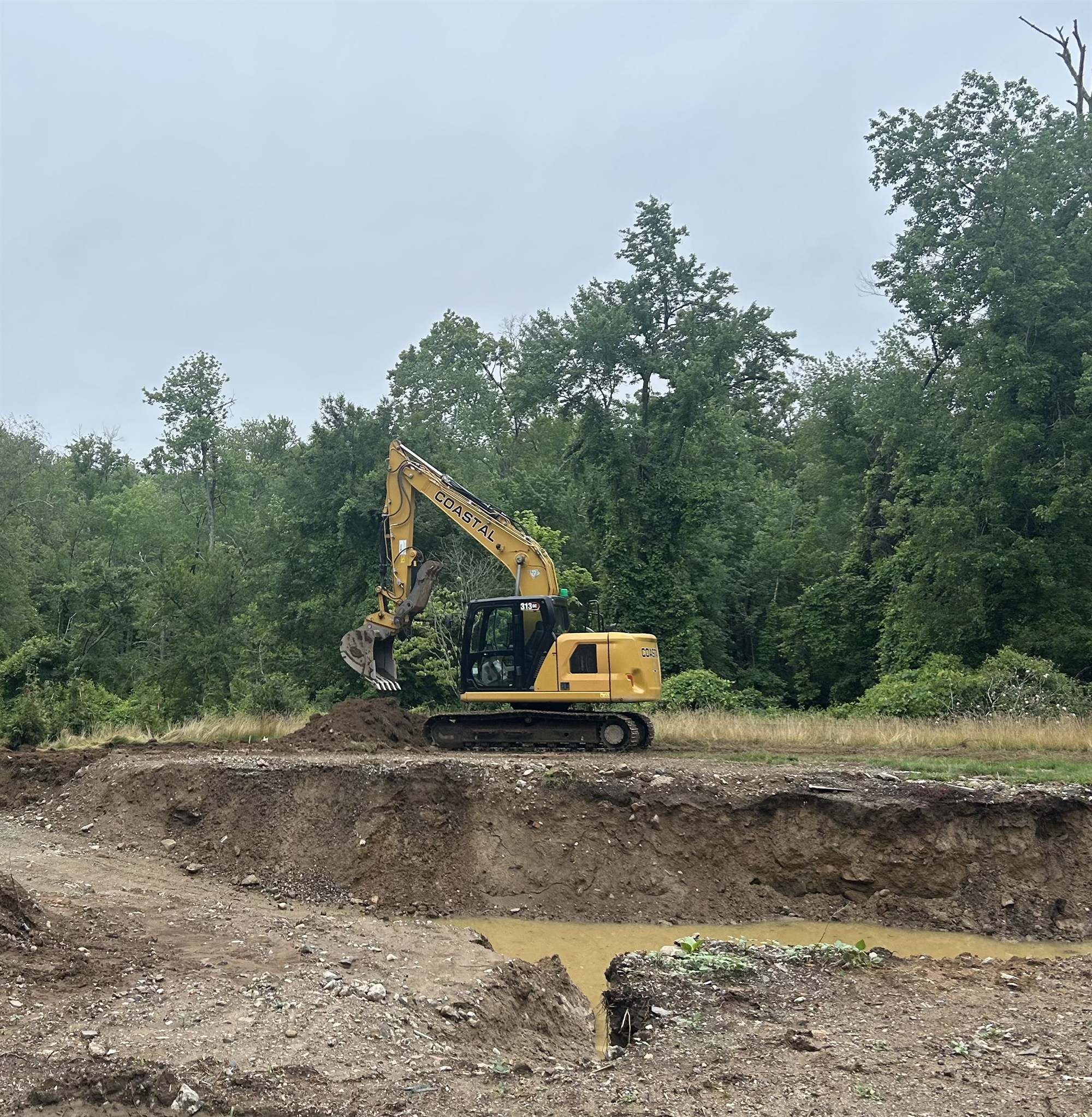 CLH excavator clearing land and shaping a pond